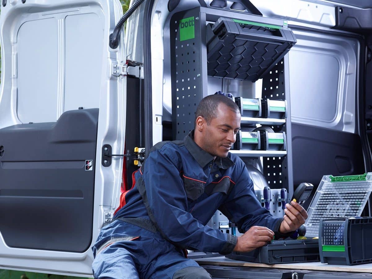 man leaning on rear of van with open doors - fitted with bott van racking and bott boxes for small tool and parts storage