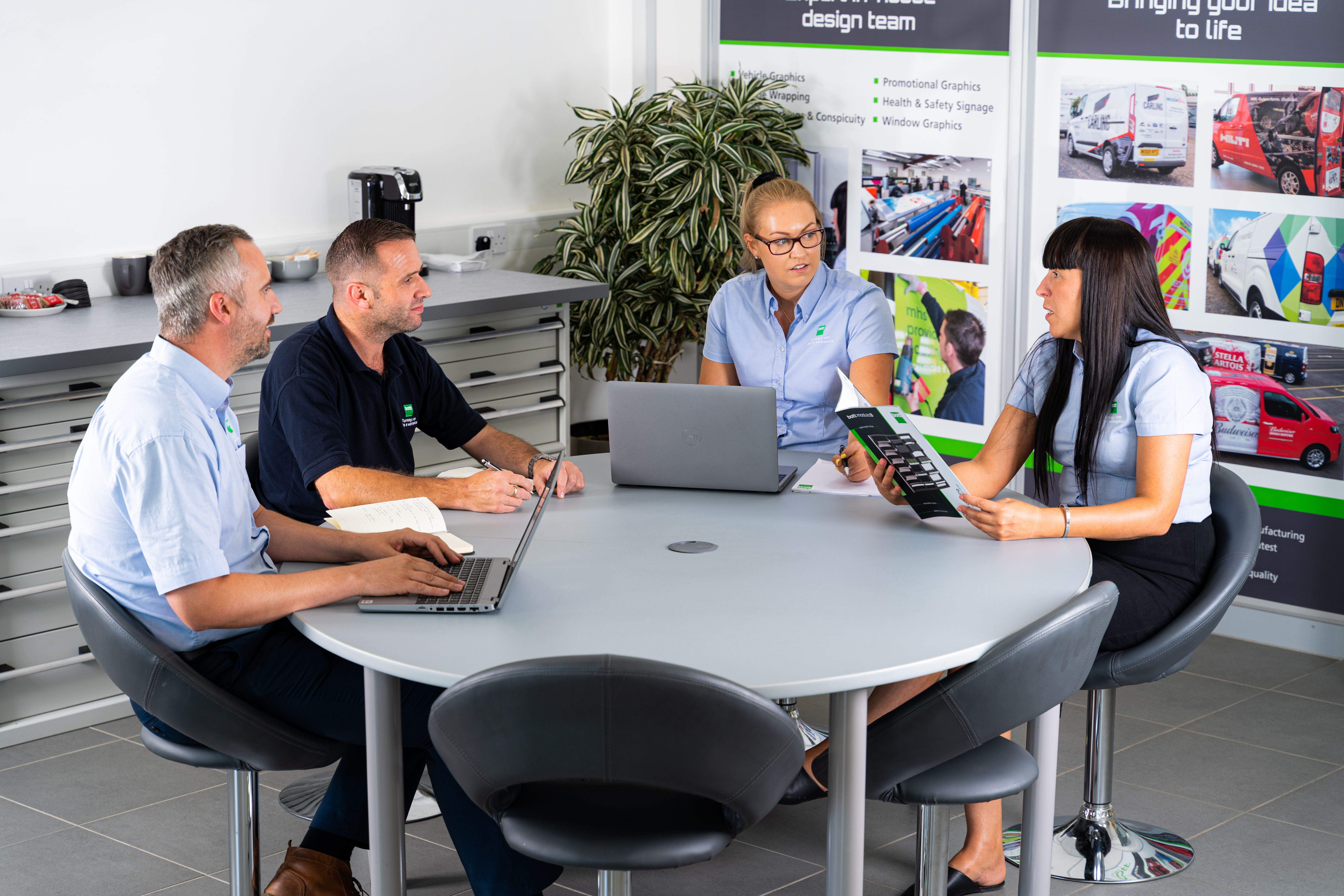 four bott employees in meeting at round table - discussing custom van racking & workplace storage