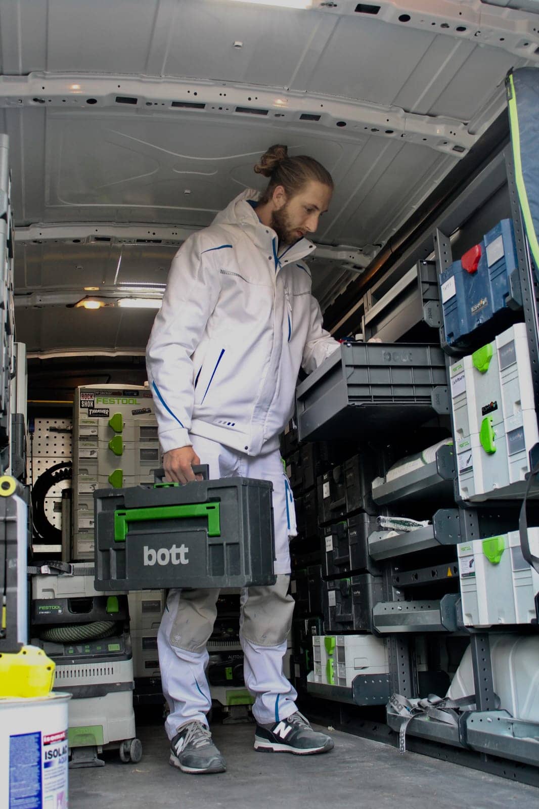 man in van fitted with van racking - holding bott box & looking for item in van racking storage box